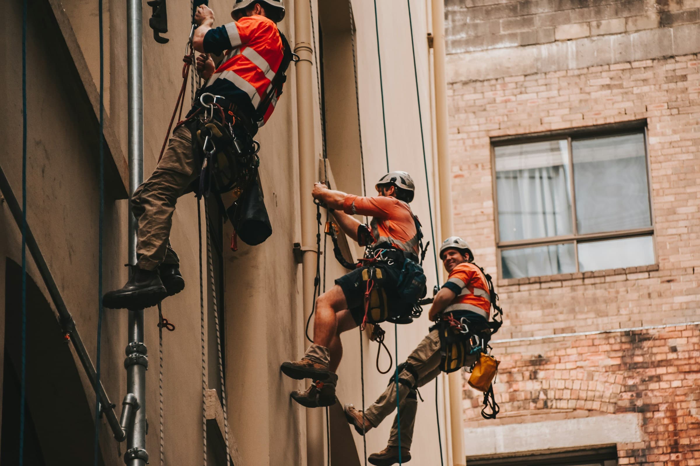 Rope-access tradies in hi-vis working at height on an Australian site