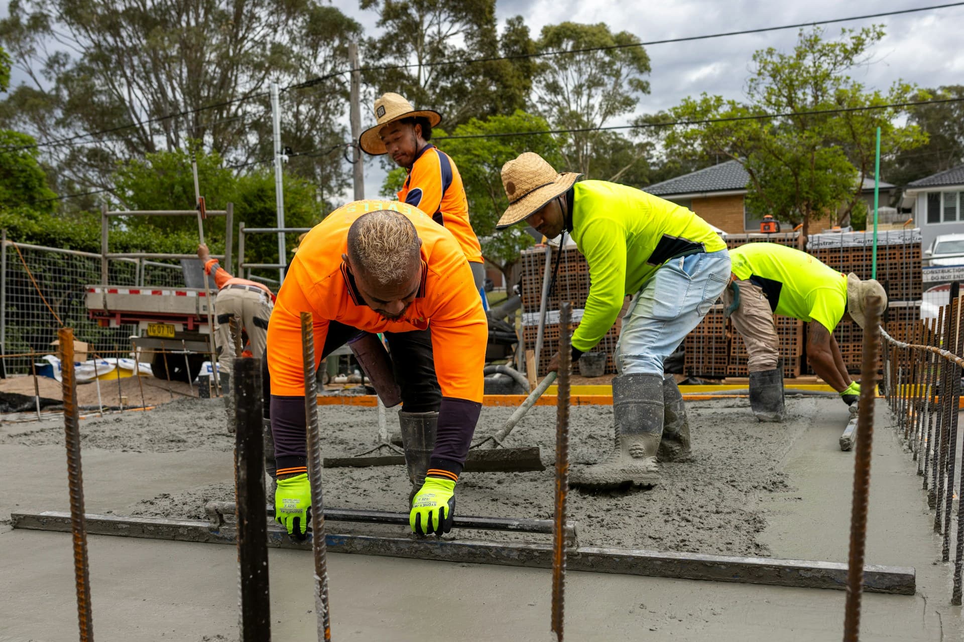A crew in hi-vis screeding wet concrete over steel reinforcement on site