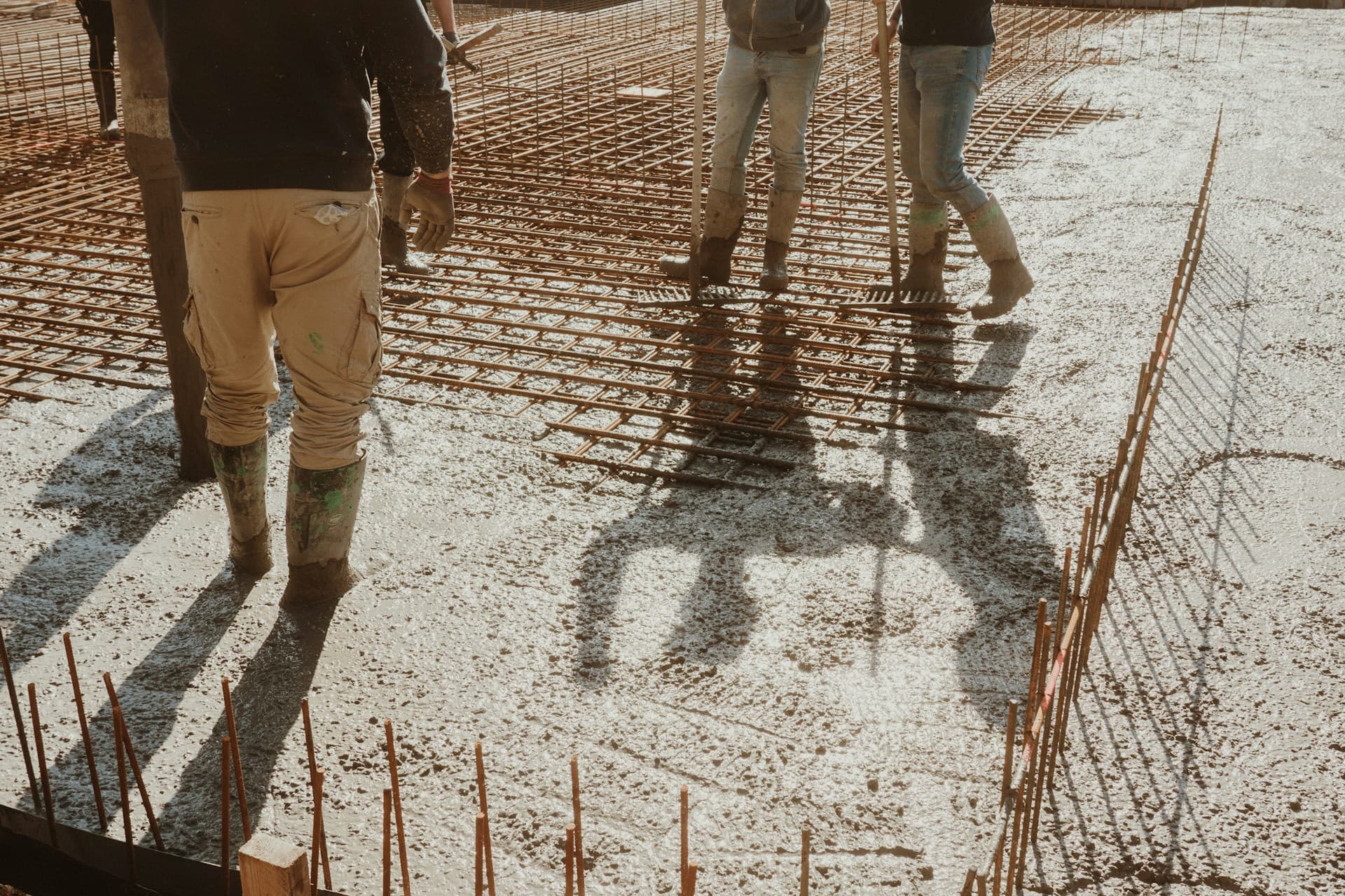 Concreting — workers spreading wet concrete over steel mesh reinforcement