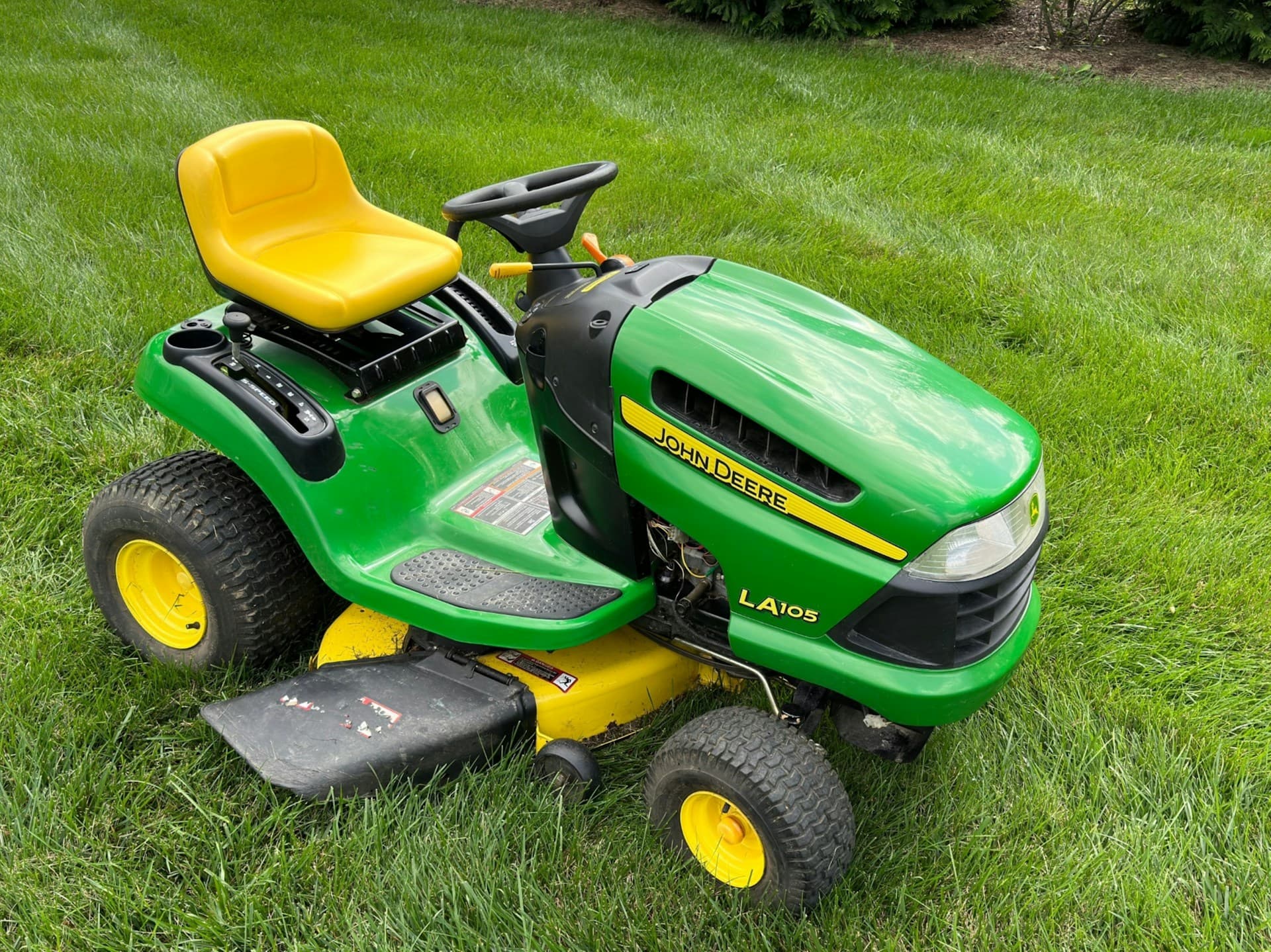 Green and yellow ride-on mower parked on a lawn