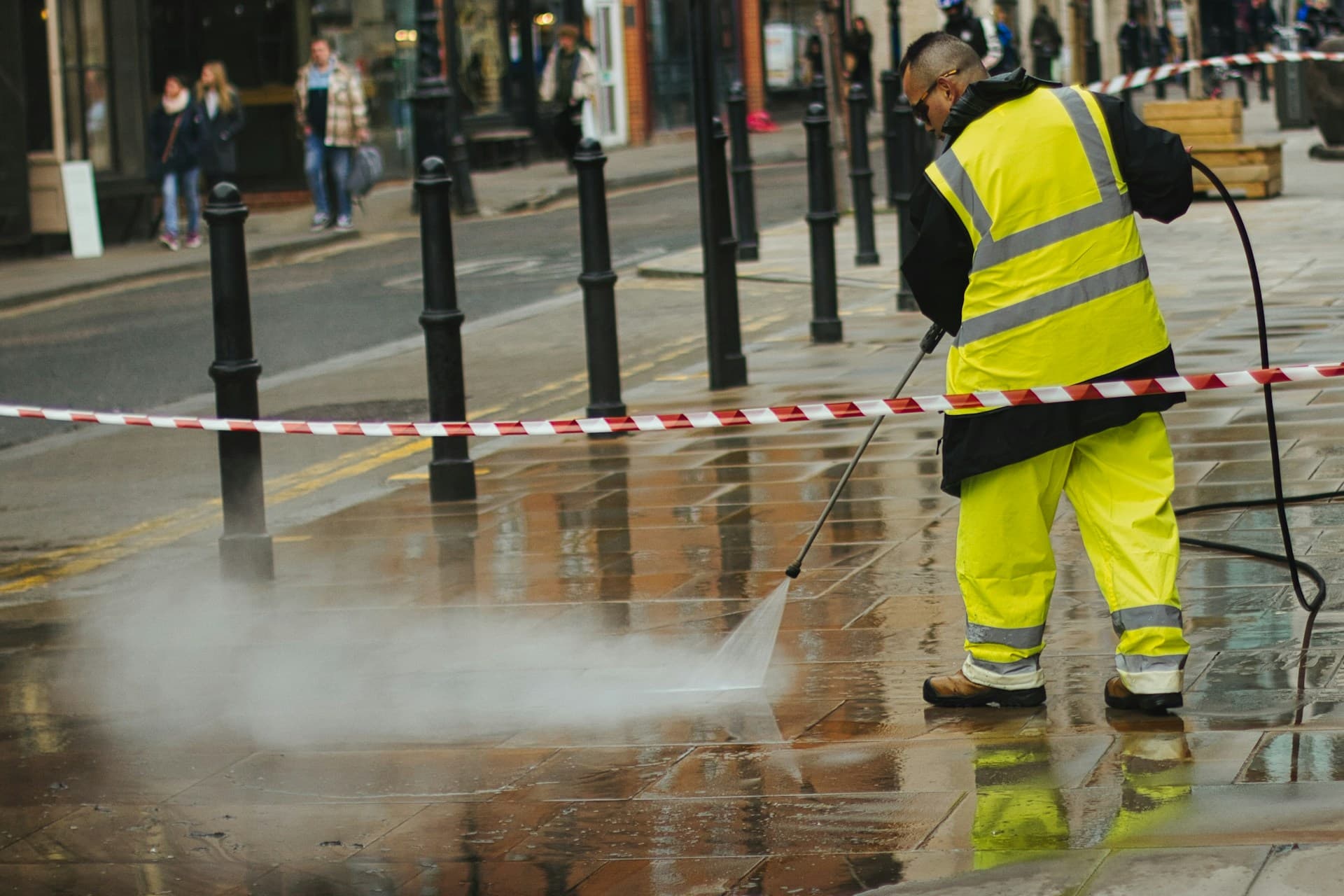 Maintenance — a worker pressure-washing a paved surface