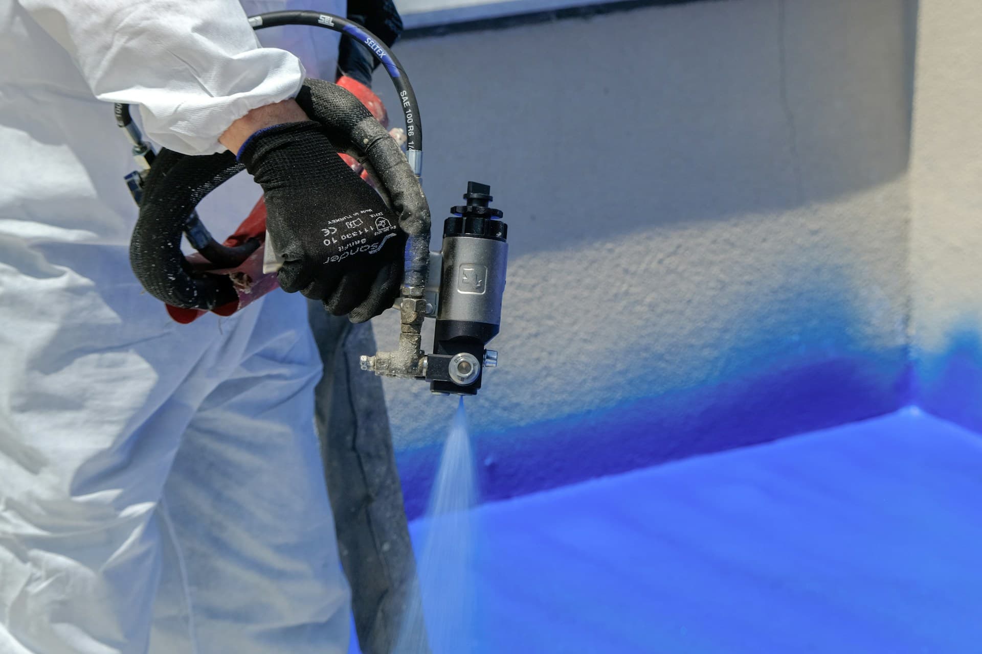 Painting — a worker in coveralls applying spray coating