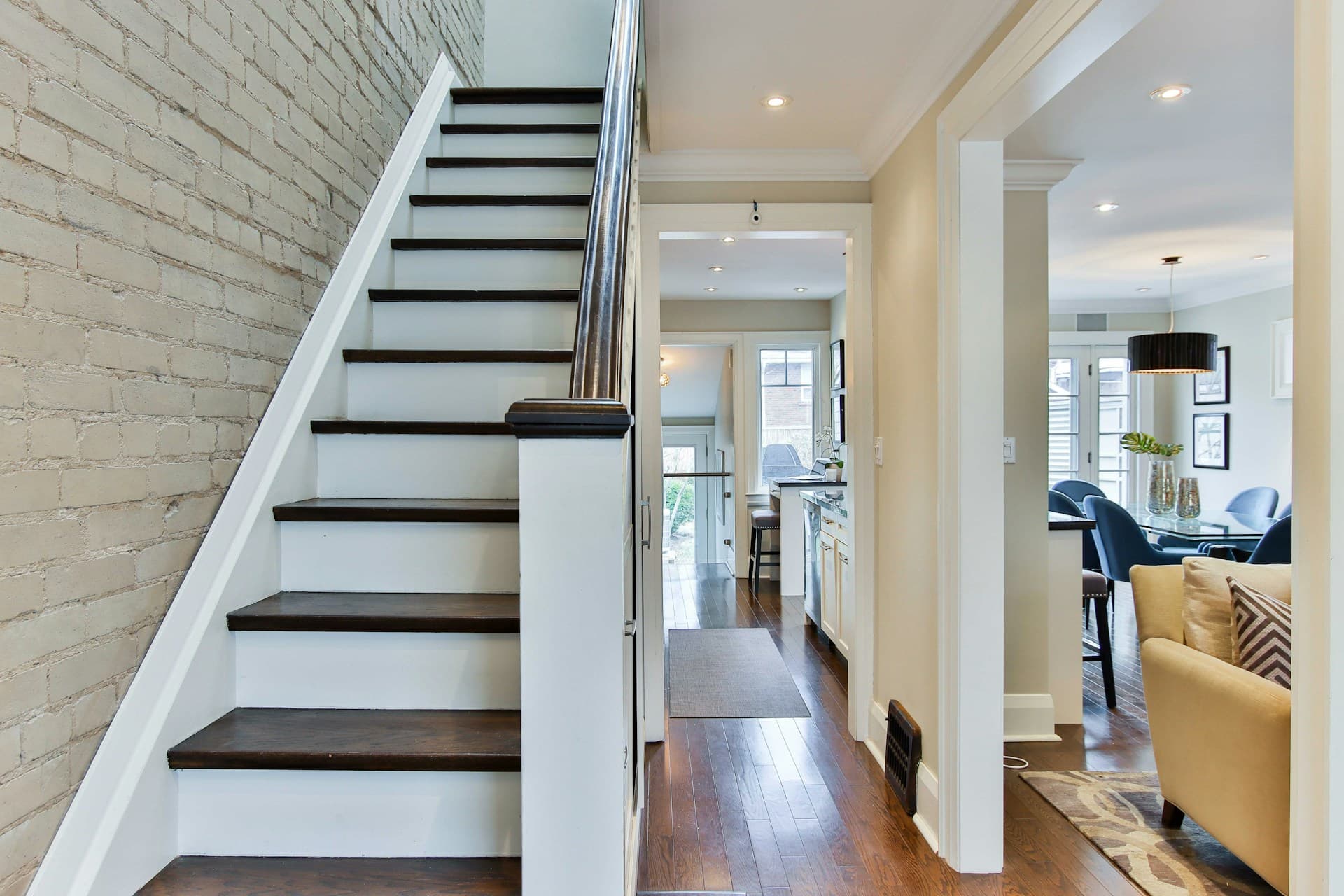 Interior timber staircase with dark treads beside an exposed painted brick wall